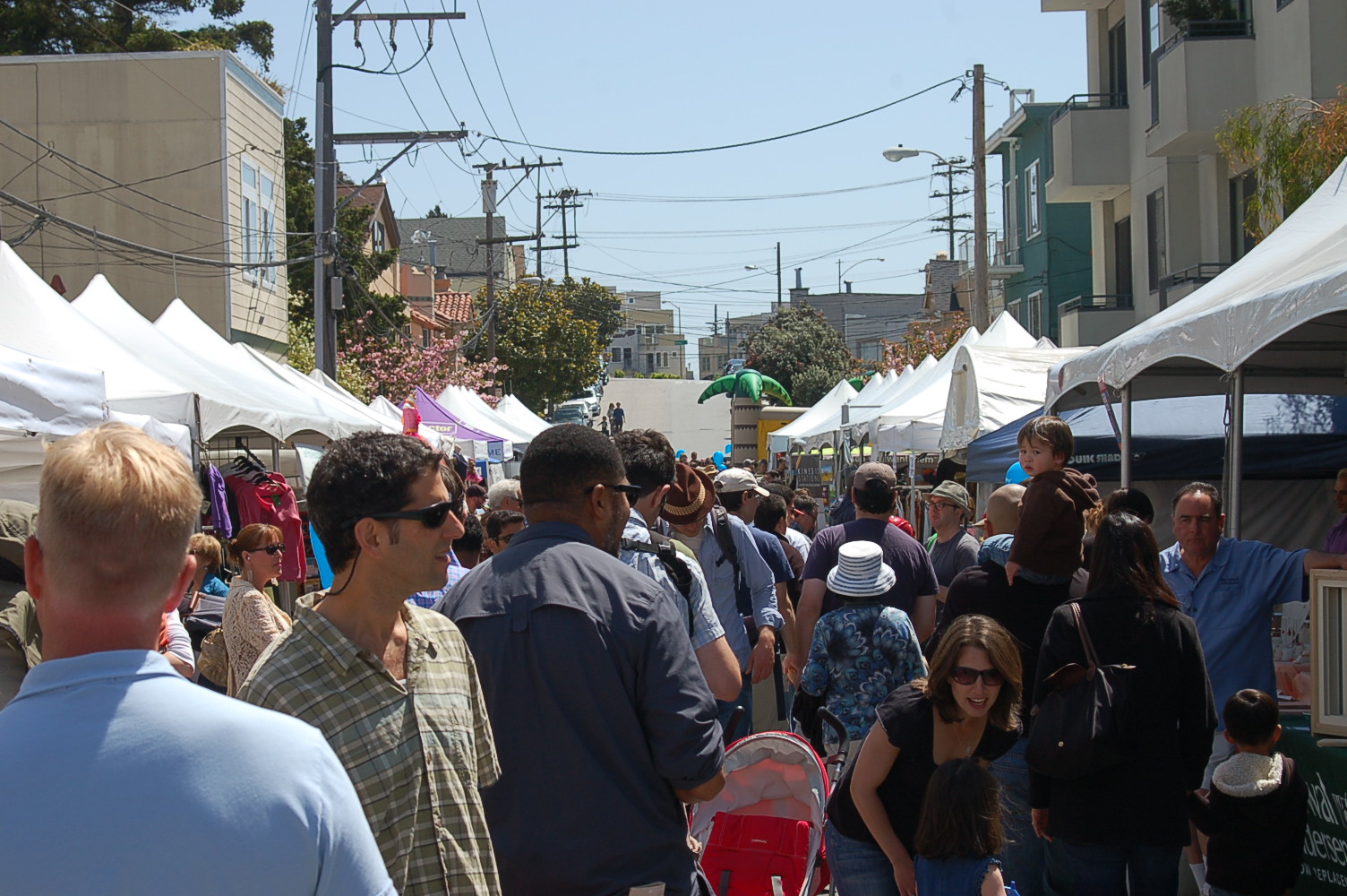 a crowd of people are walking through an outdoor market