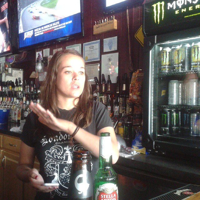 a woman is sitting at the bar with a beer