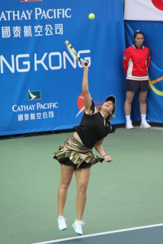 a tennis player leaps up and reaches to serve