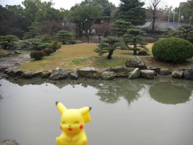 a small yellow toy sitting next to a pond