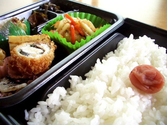 two black containers filled with rice, meat and vegetables