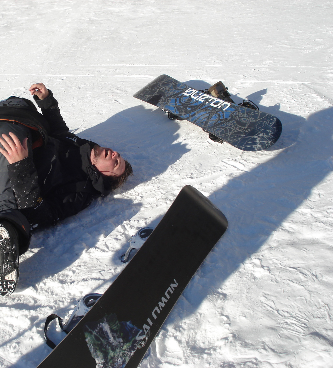 man on snowboard laying in the snow with his feet up