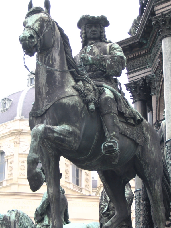 the statue of a man on a horse is located in front of a building
