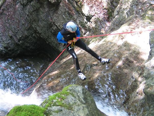 a man wearing a helmet on a rope going up a river