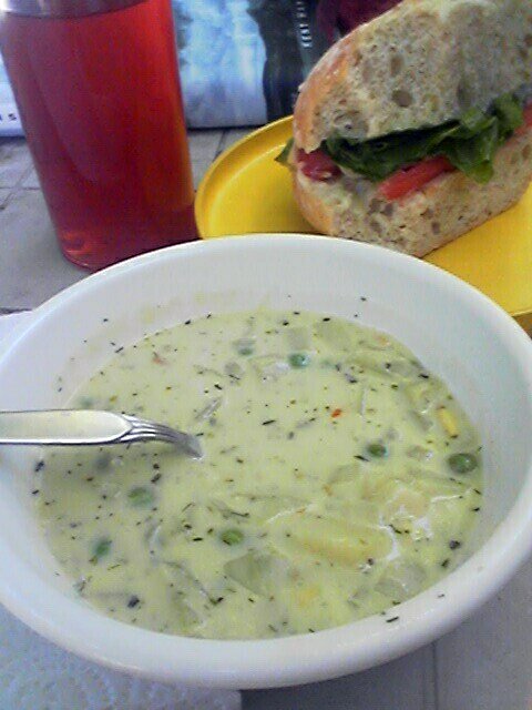 a bowl of soup, a sandwich and a drink are on the table