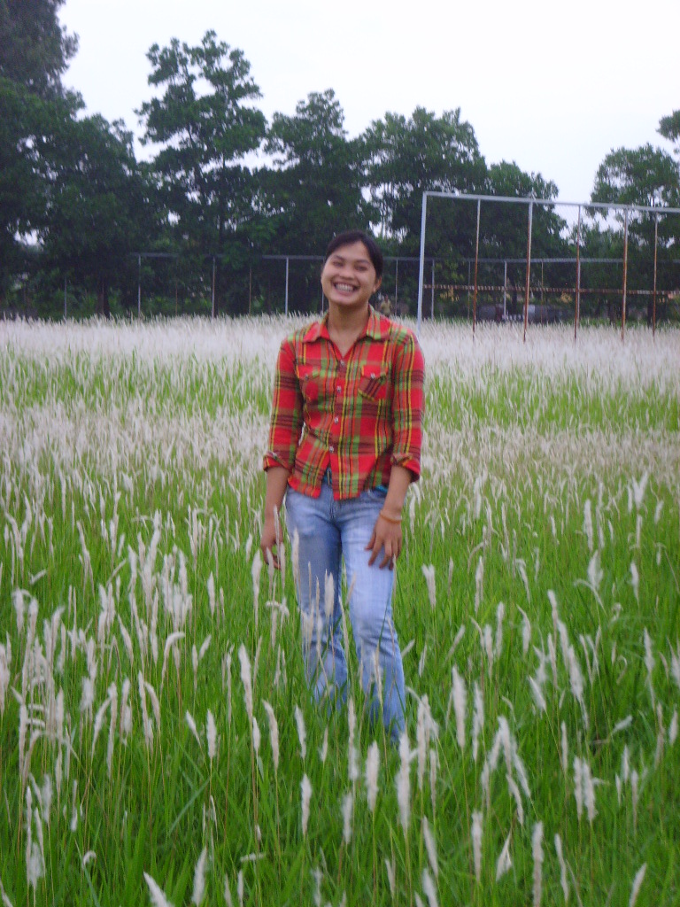 a woman wearing a shirt standing in a field