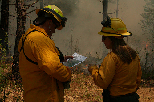 two firefighters dressed in yellow suits and helmet standing next to each other