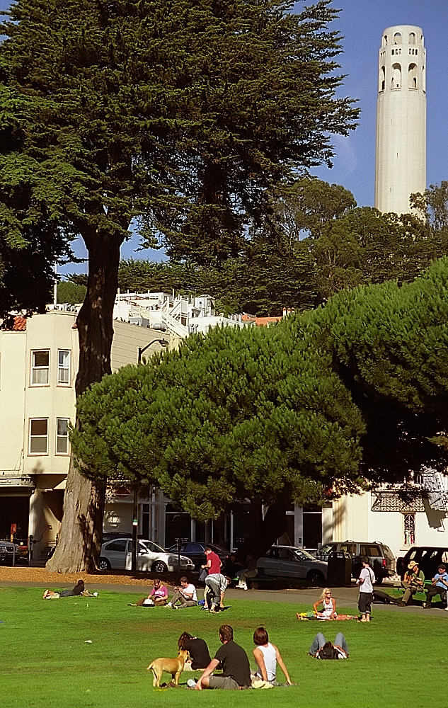 people are relaxing on the grass next to the large tower