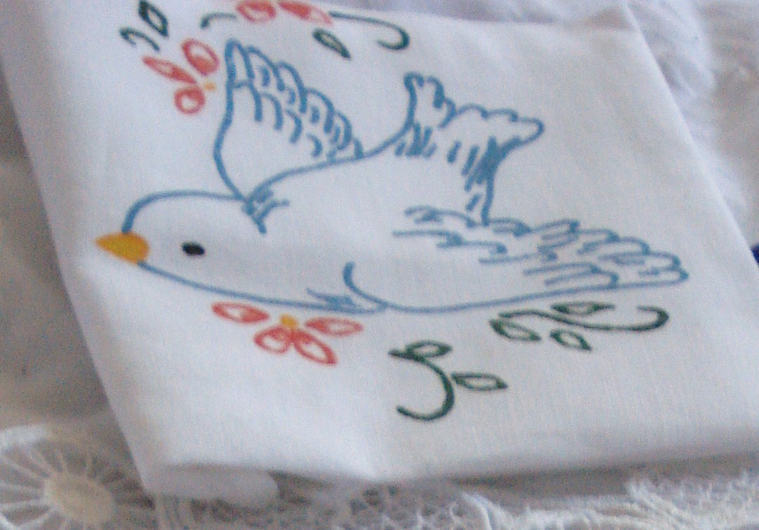 embroidered cloth with a bird on it is lying on lace