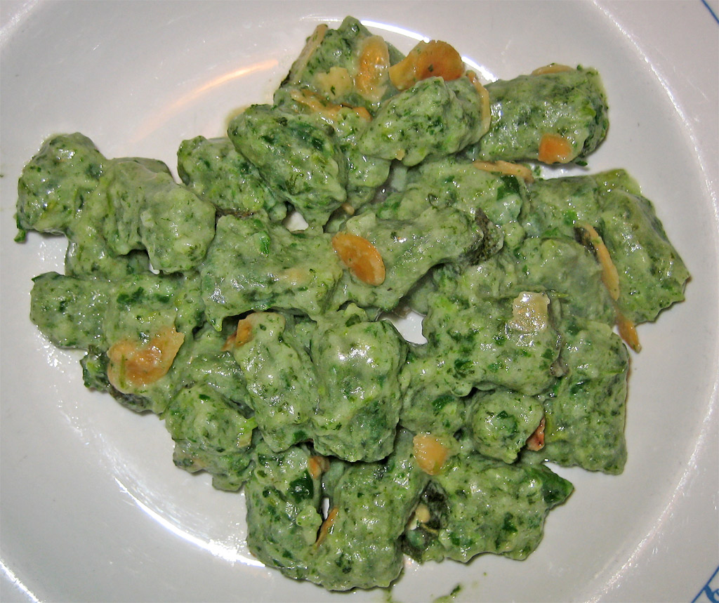 a white plate filled with green cheese and sauce