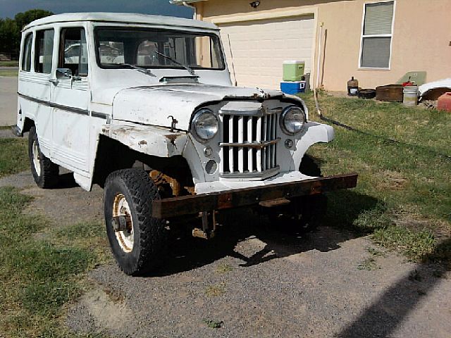 an old white truck parked on top of a field