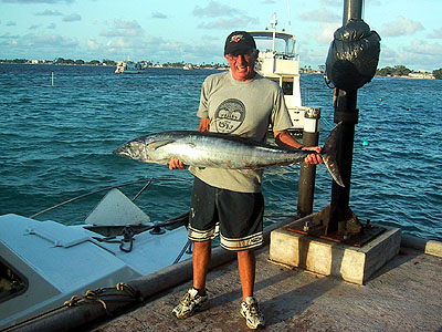 a man holds a large fish while standing on the dock