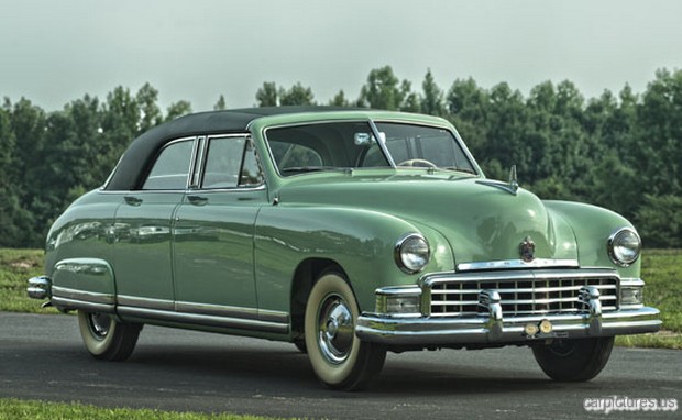 a large green car sits on a paved road