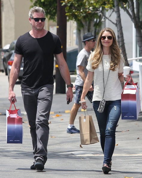 the man and woman are carrying bags on a city street