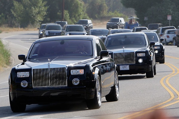 limousines are driving down a highway with trees in the background