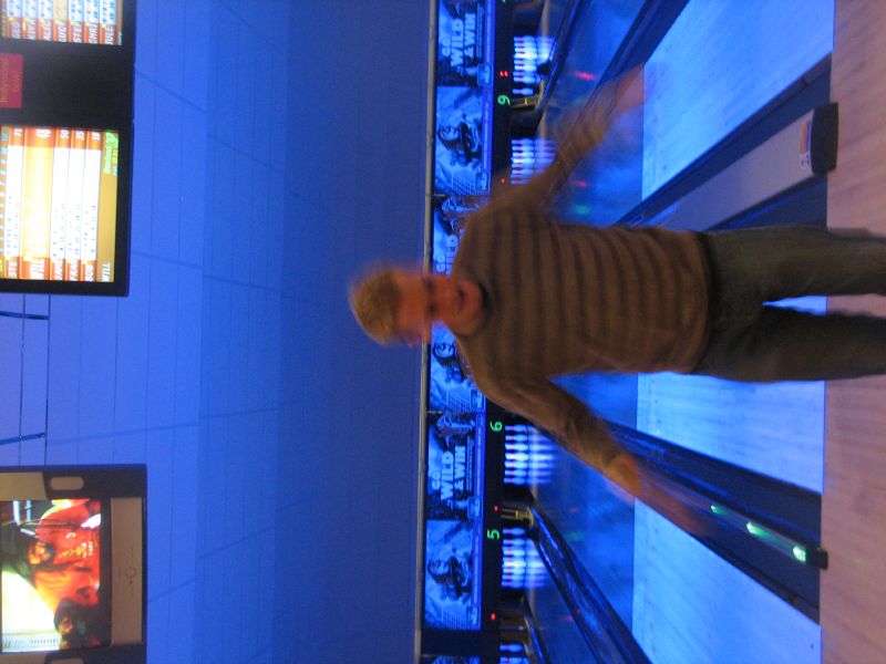 a man bowling in the bowling alley with three bowling lanes behind him