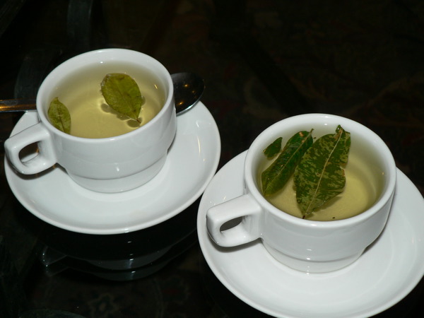 the two cups are filled with green tea and there is a spoon