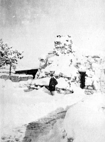a snow covered stone structure with a man near the entrance