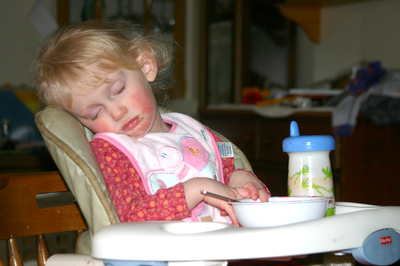 a toddler sitting in her high chair with a bowl and spoon