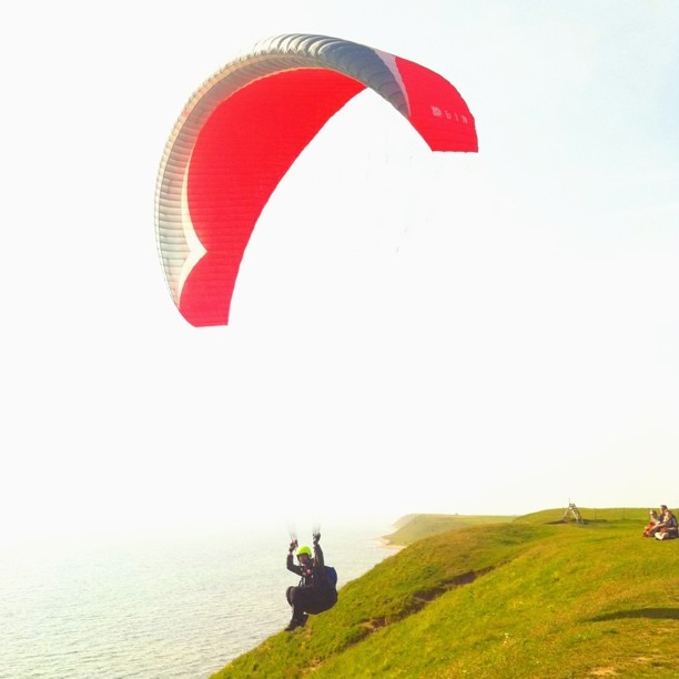 a person flying a large kite on top of a cliff