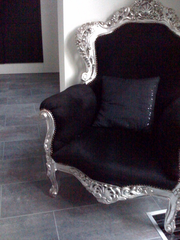 a decorative silver and black chair sitting in the corner of a room
