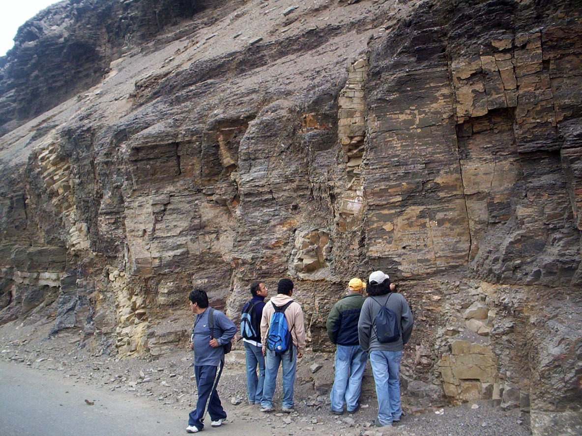 four people are walking in front of a cliff