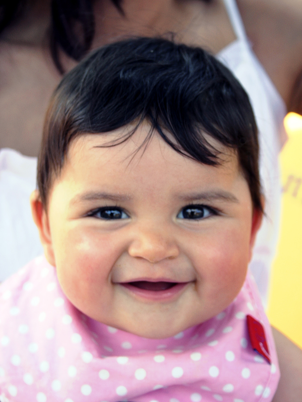 a smiling baby wears pink and white polka dots