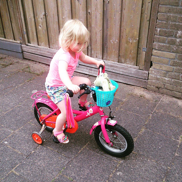 a little girl riding on a pink bike