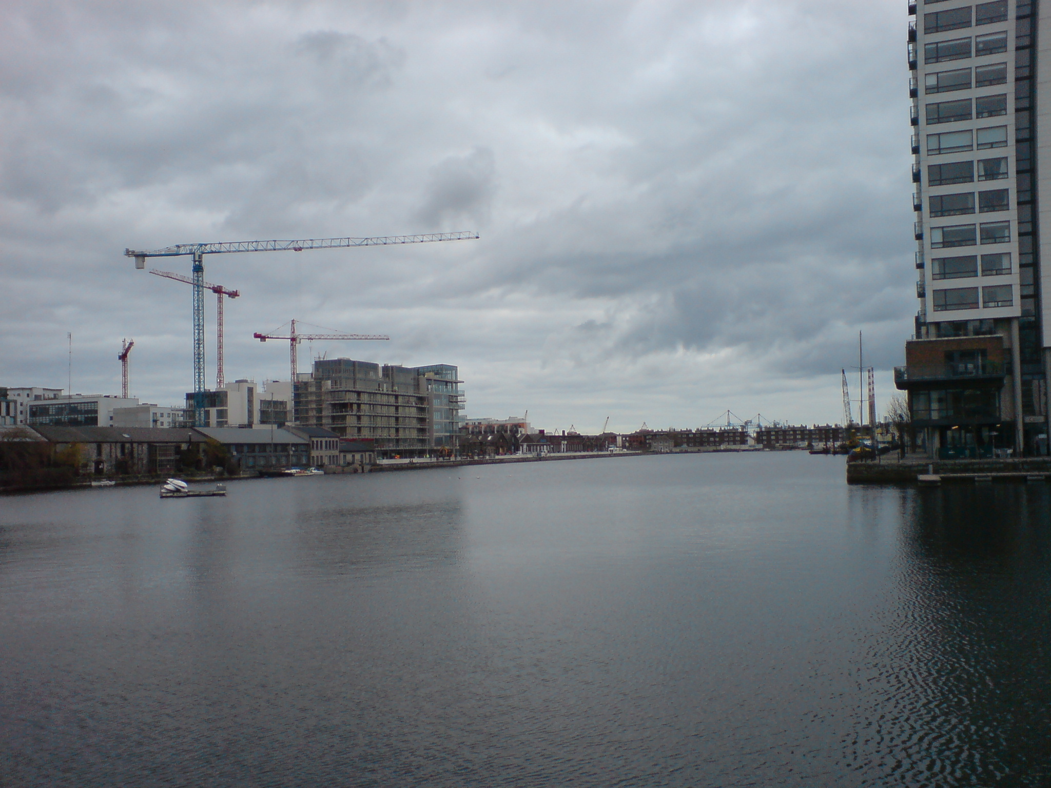 buildings near the water and construction crane in background