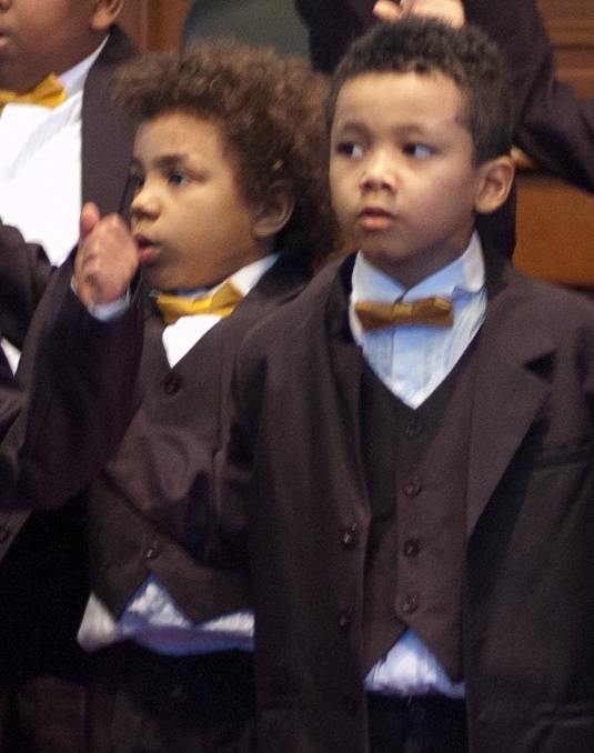 two little boys are standing with others wearing their suits