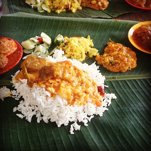 rice and meat served on a banana leaf with other foods