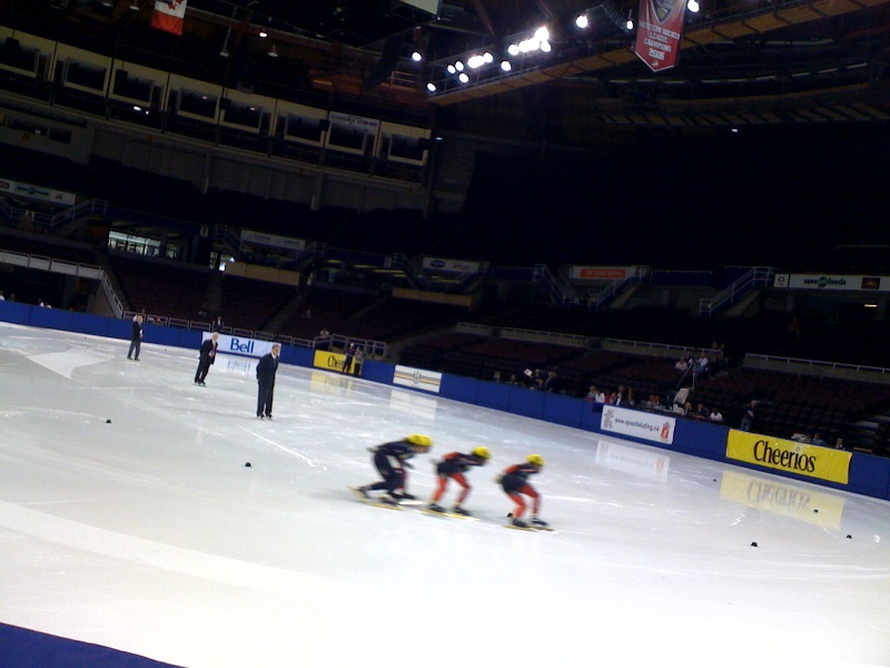 three people skating on an ice rink on a snowy day