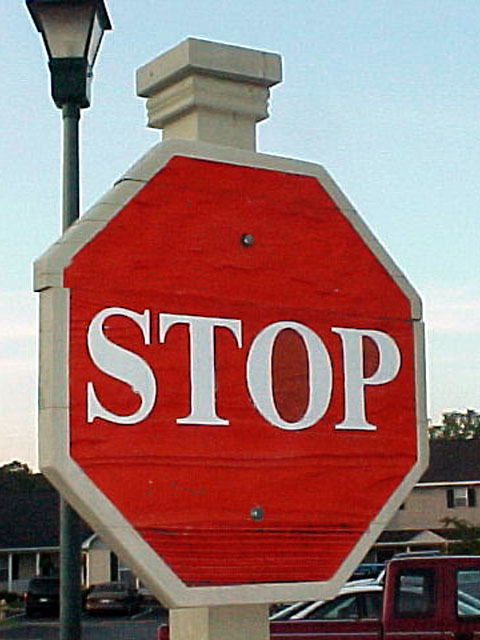 a large stop sign sitting next to a lamp post