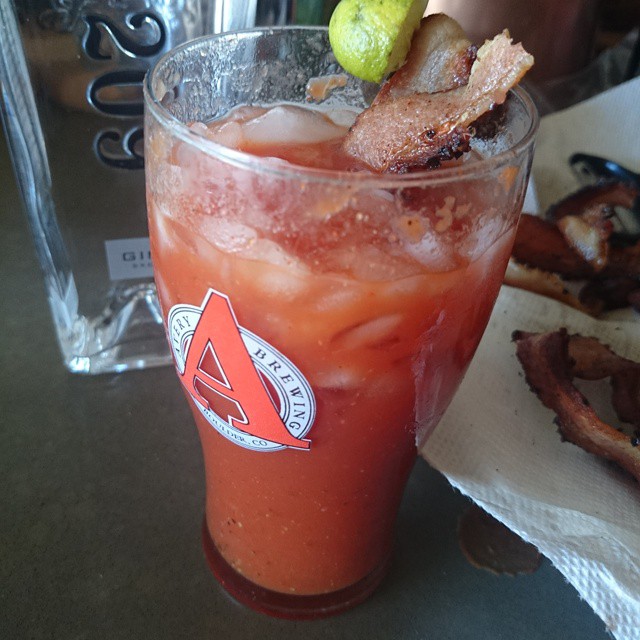 a closeup of a y drink with bacon on the side