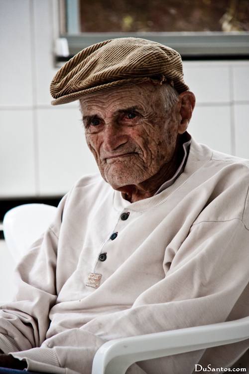 an elderly gentleman wearing a hat is seated