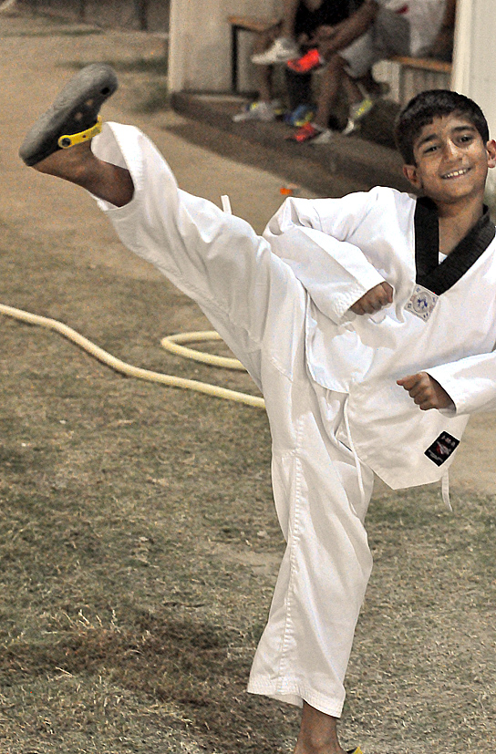 boy practices karate moves in front of some people