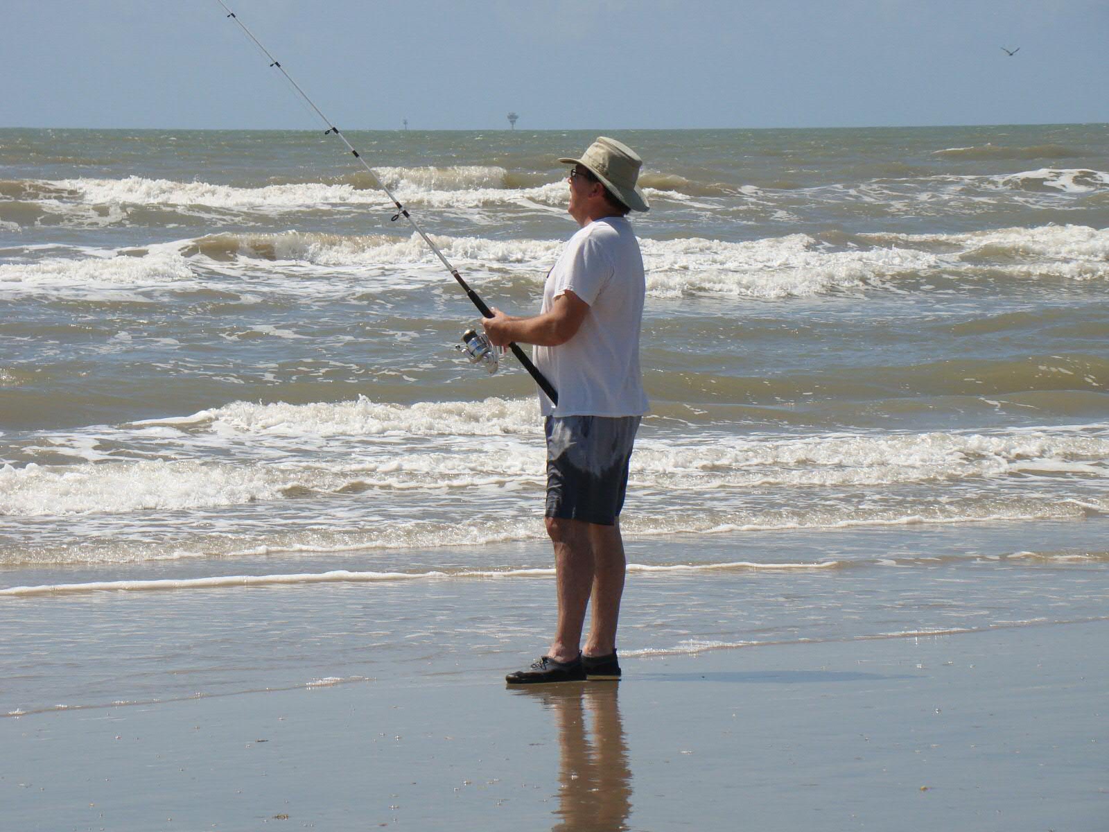 a man holding a fishing pole on the beach