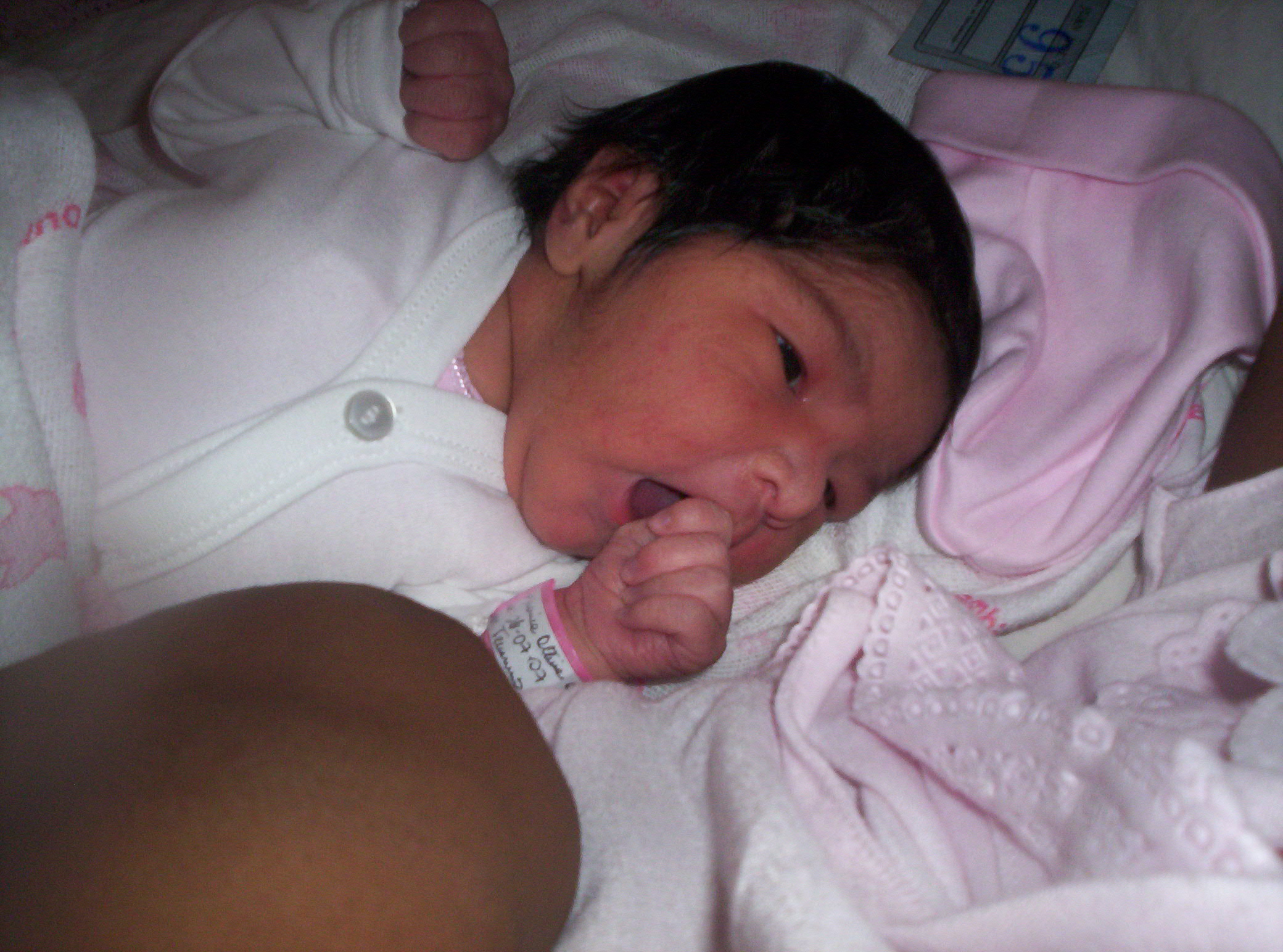 a small baby in a hospital gown being held by someone