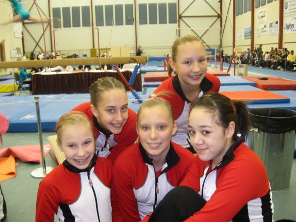 a group of girls in red jackets on some gymnastics equipment
