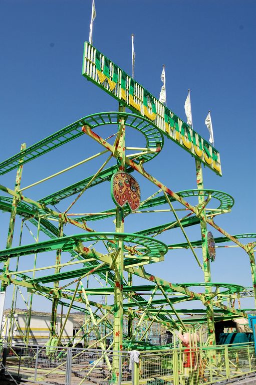a green coaster ride with flags on the top of it