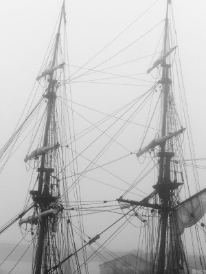 a ship sailing in the foggy ocean near a boat