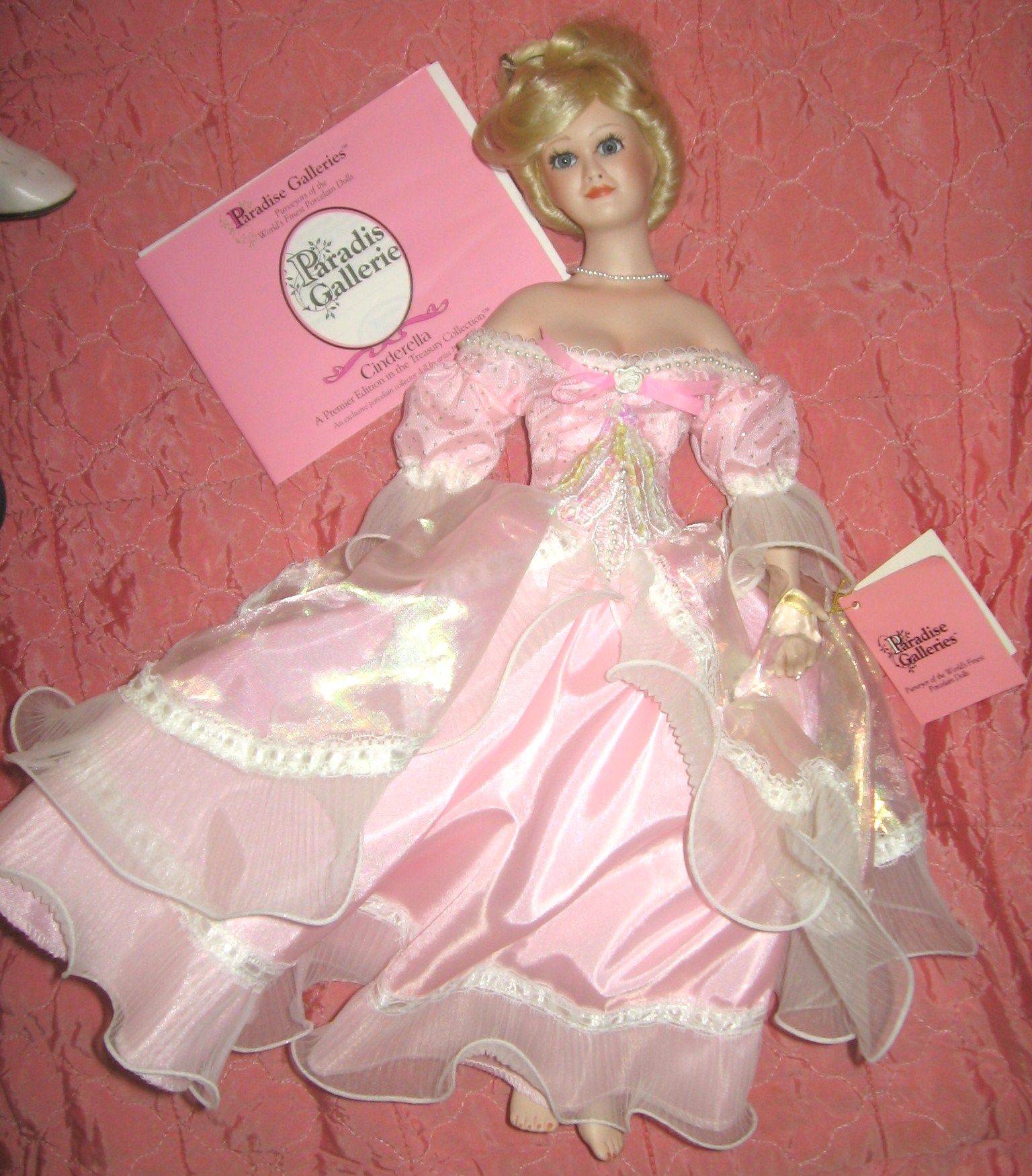 a toy wearing a pink dress holding a book