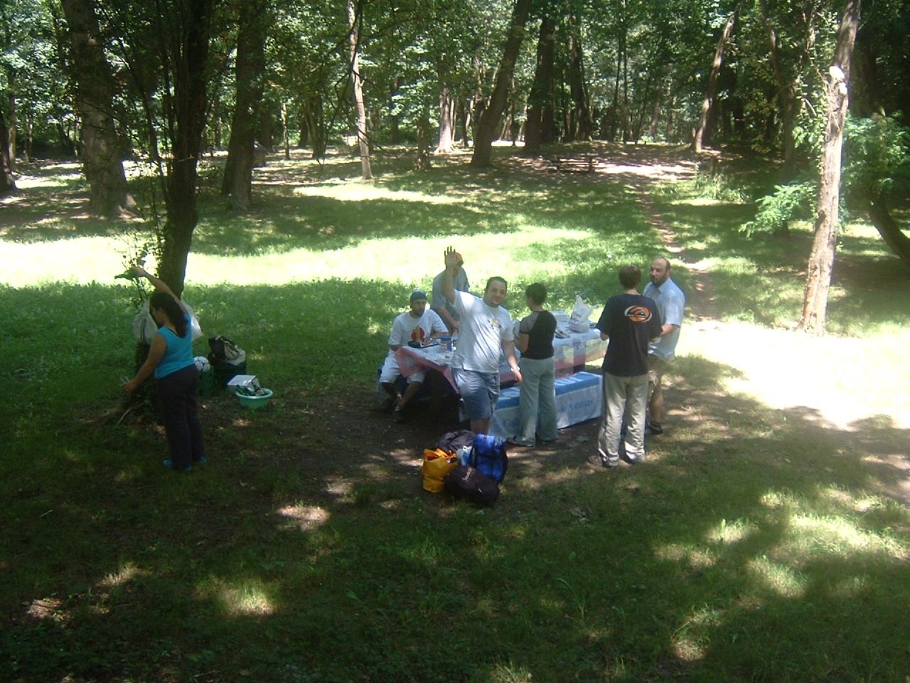 a group of people sitting around each other and eating in a park