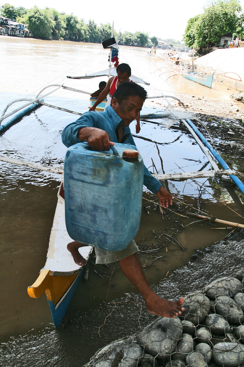 some men are in the water carrying barrels and plastic