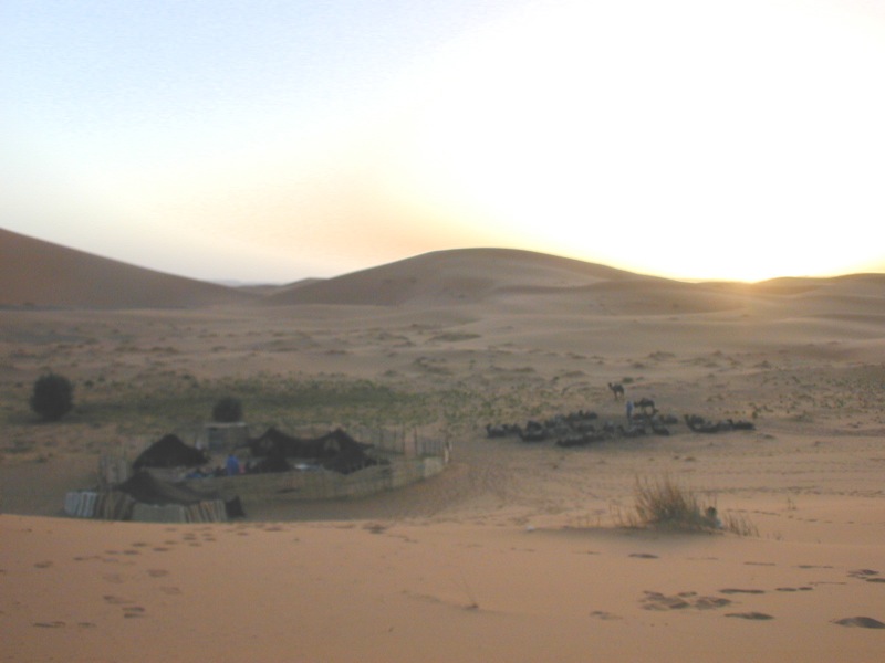 a view of the desert at sunset with a car in the foreground