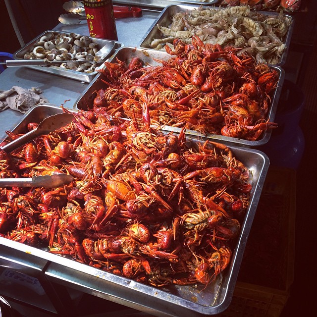 a table with trays of cooked crawfish and shrimp