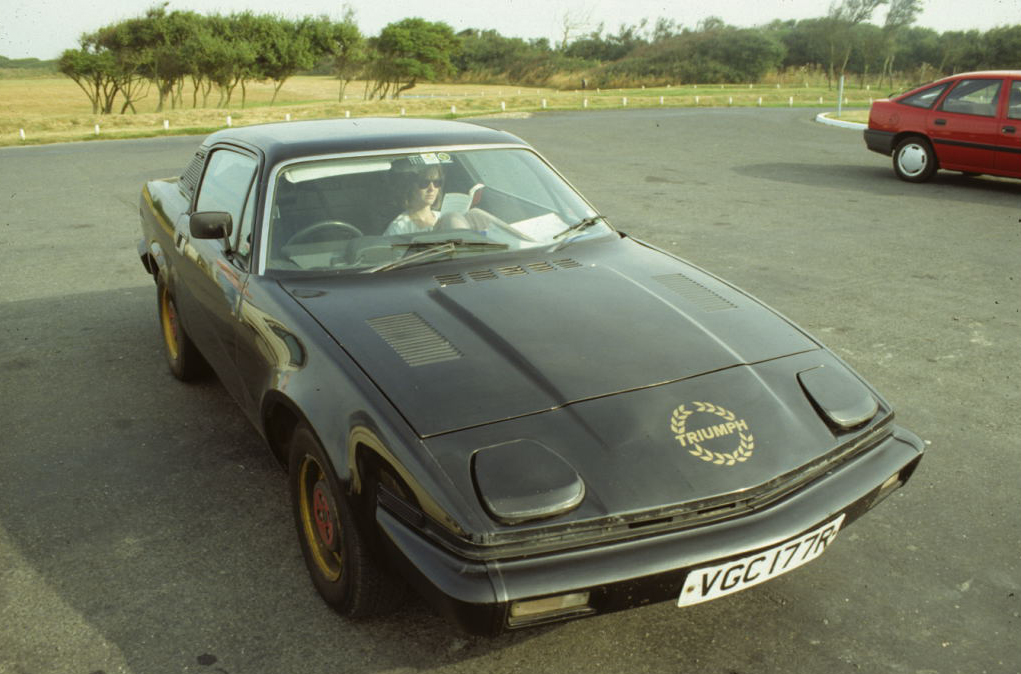 an older model car is parked in a parking lot