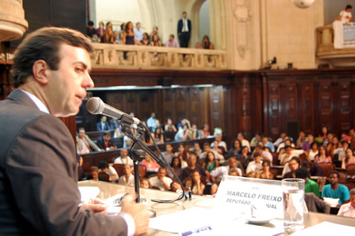 a man speaking into a microphone in front of a crowd