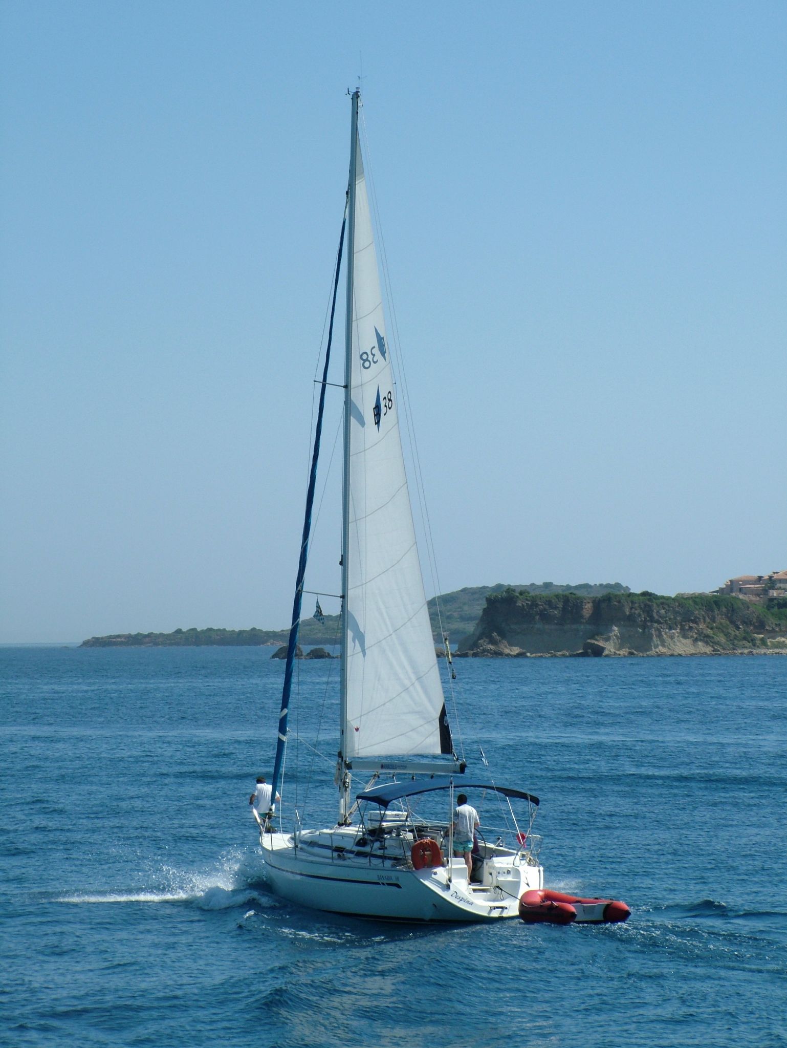 a white sailboat with people on it in the ocean