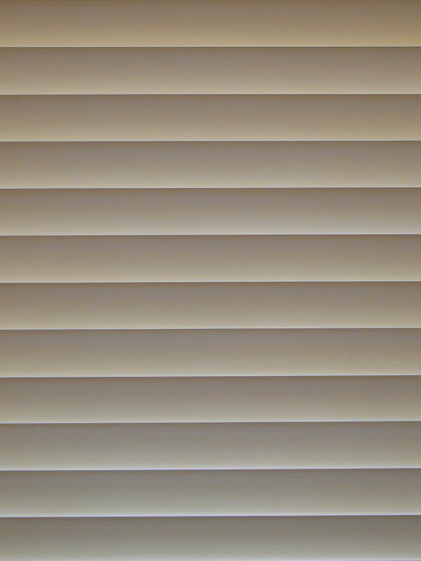a bathroom with tan blinds covering the window